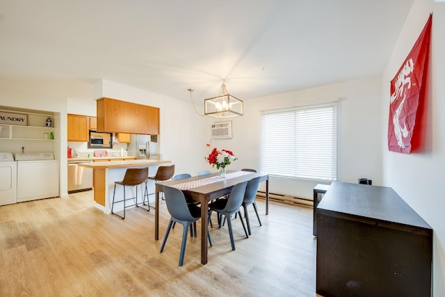 dining space with an inviting chandelier, light wood-style flooring, baseboard heating, and independent washer and dryer