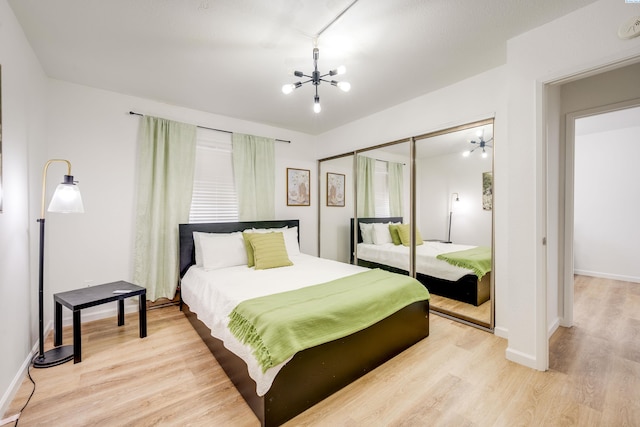 bedroom featuring light wood-style floors, a closet, baseboards, and a notable chandelier