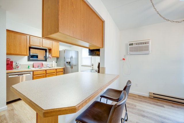 kitchen featuring a breakfast bar area, a wall mounted AC, appliances with stainless steel finishes, a sink, and light wood-type flooring