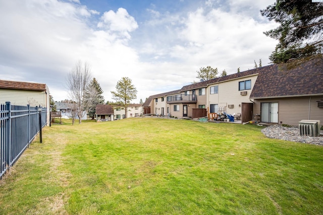 view of yard with a residential view, fence, and central AC