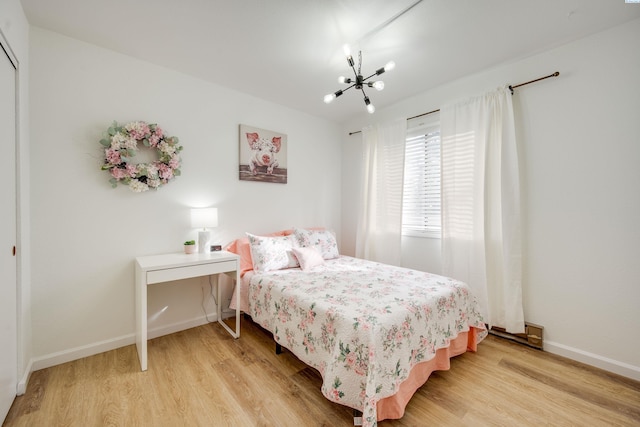 bedroom with a chandelier, a closet, baseboards, and light wood-style floors