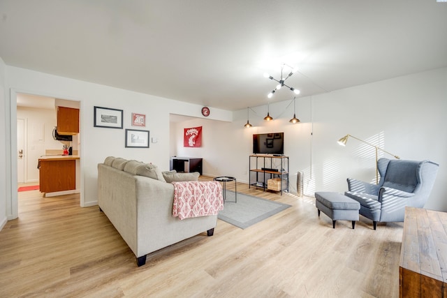 living area with light wood-style flooring and a notable chandelier