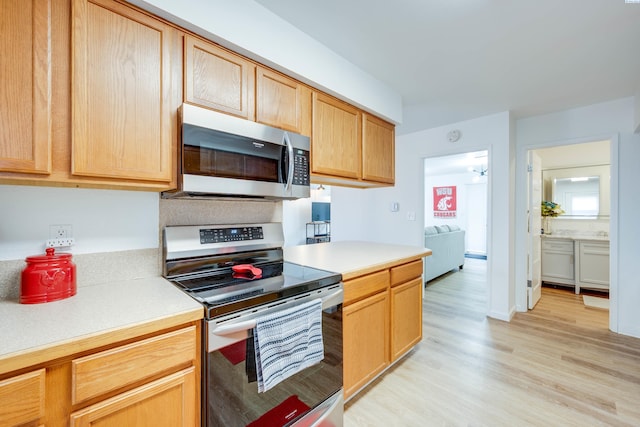 kitchen with light wood finished floors, light brown cabinets, appliances with stainless steel finishes, and light countertops