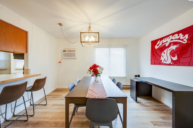 dining area featuring a chandelier, light wood-type flooring, a wall mounted air conditioner, and a baseboard radiator