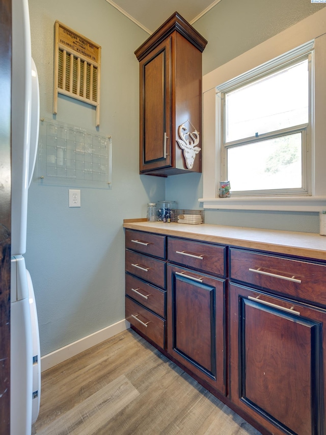 kitchen with fridge, baseboards, light wood-style flooring, and light countertops