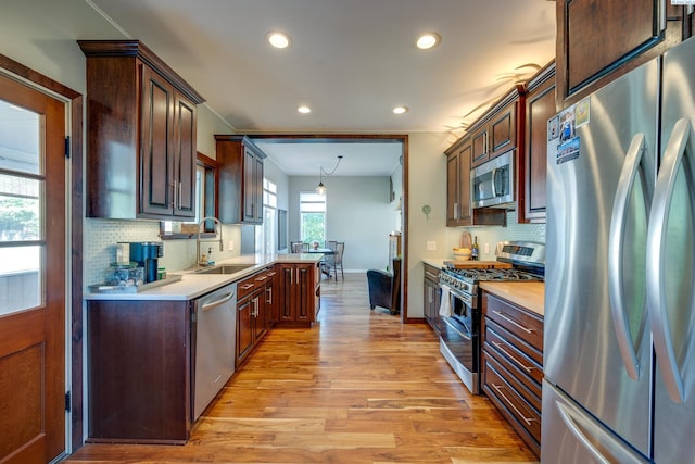 kitchen featuring appliances with stainless steel finishes, light countertops, light wood-style floors, and a sink