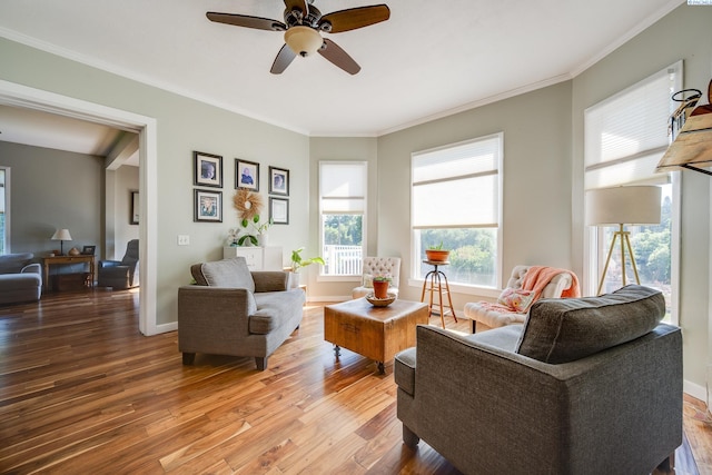 living area featuring baseboards, crown molding, a ceiling fan, and wood finished floors