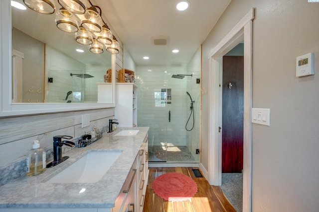 full bath with wood finished floors, a stall shower, backsplash, and a sink