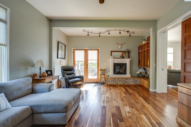 living area with wood-type flooring, a glass covered fireplace, and rail lighting