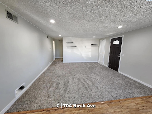interior space with a textured ceiling and carpet flooring
