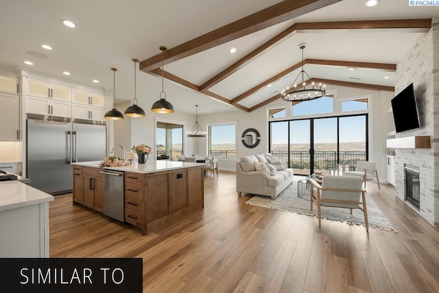 kitchen with a spacious island, white cabinetry, an inviting chandelier, stainless steel appliances, and a fireplace