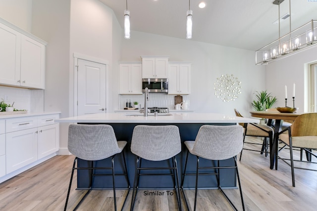 6482 W 30th Pl, Kennewick, WA 99338 - kitchen featuring stainless steel microwave, light countertops, a sink, light wood-style floors, and a kitchen island with sink