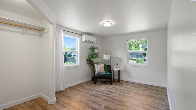 654 Cottonwood Dr, Richland, WA 99352 - sitting room with a wall unit AC, light wood finished floors, baseboards, and a textured ceiling