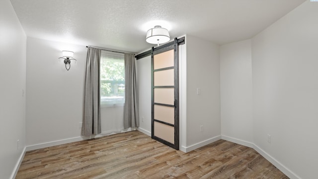 654 Cottonwood Dr, Richland, WA 99352 - spare room with light wood finished floors, a textured ceiling, baseboards, and a barn door