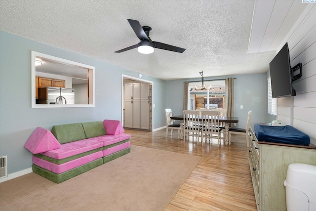 2519 W Grand Rhonde Pl, Kennewick, WA 99336 - living area featuring a chandelier, light wood-style flooring, a textured ceiling, a ceiling fan, and baseboards