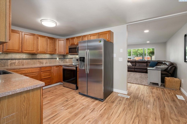 2519 W Grand Rhonde Pl, Kennewick, WA 99336 - kitchen with appliances with stainless steel finishes, light wood-style floors, baseboards, and decorative backsplash