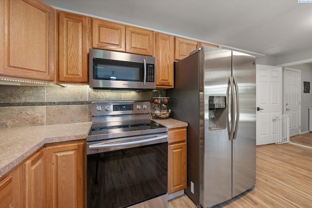 2519 W Grand Rhonde Pl, Kennewick, WA 99336 - kitchen with appliances with stainless steel finishes, tasteful backsplash, light countertops, and light wood finished floors