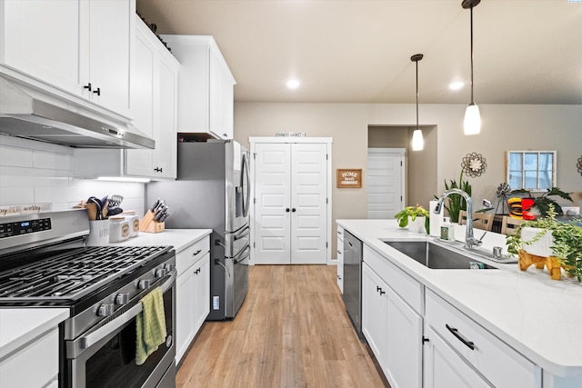 7867 Blanchard Loop, West Richland, WA 99353 - kitchen featuring stainless steel appliances, under cabinet range hood, white cabinets, light wood-style floors, and hanging light fixtures