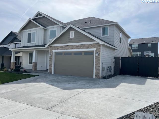 7867 Blanchard Loop, West Richland, WA 99353 - view of front of home with stone siding, driveway, a porch, and board and batten siding