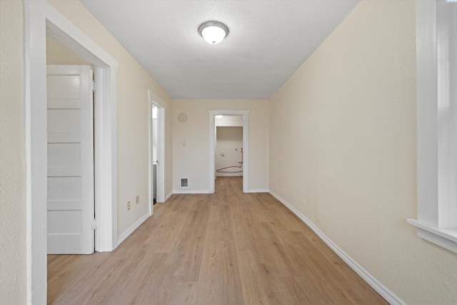 corridor featuring light hardwood / wood-style floors and a textured ceiling