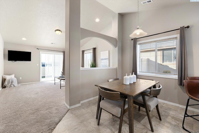 dining room with lofted ceiling, light carpet, and a textured ceiling