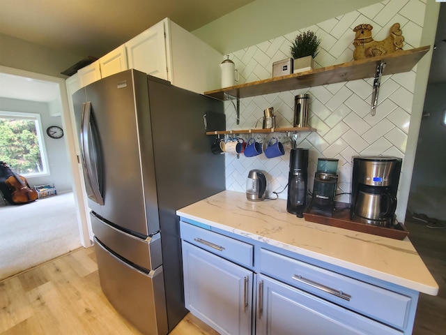7218 W 15th Ave, Kennewick, WA 99336 - kitchen with freestanding refrigerator, tasteful backsplash, light stone counters, light wood-style floors, and white cabinets