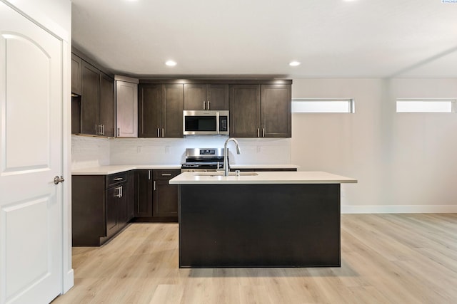 10402 Kokanee Dr, Pasco, WA 99301 - kitchen featuring backsplash, appliances with stainless steel finishes, light wood-style floors, a sink, and dark brown cabinetry