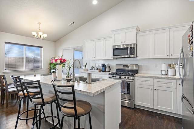 kitchen featuring sink, white cabinetry, pendant lighting, stainless steel appliances, and a kitchen island with sink