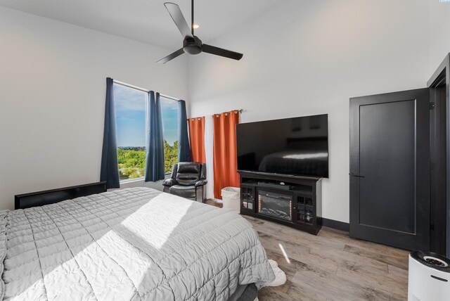 3312 Bing St, West Richland, WA 99353 - bedroom with light wood-type flooring, a towering ceiling, a fireplace, a ceiling fan, and baseboards