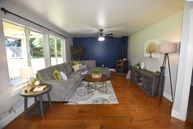 2780 Katie Rd, Kennewick, WA 99338 - living room with a ceiling fan, an accent wall, a wood stove, wood finished floors, and baseboards