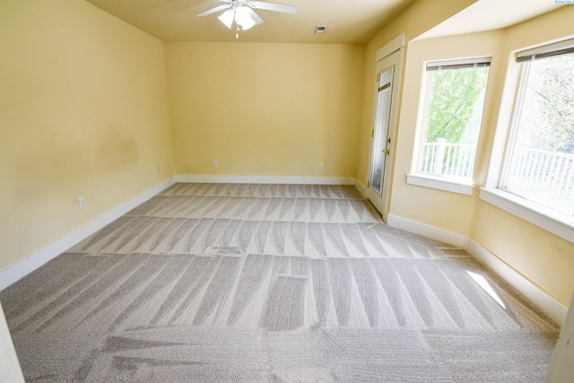 carpeted spare room featuring visible vents, baseboards, and a ceiling fan