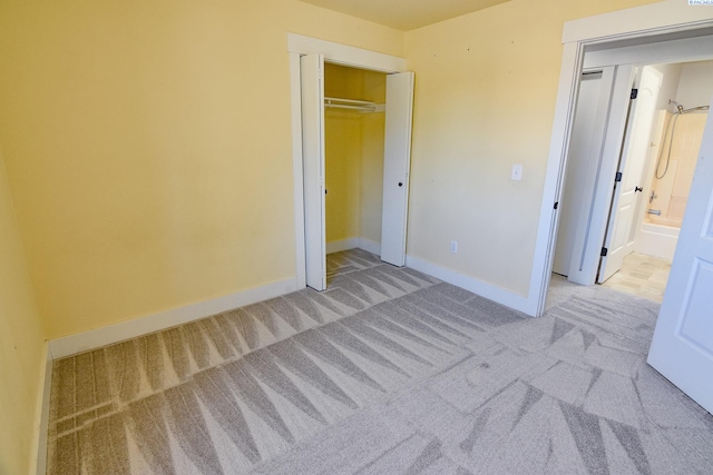 unfurnished bedroom featuring a closet, baseboards, carpet flooring, and ensuite bathroom