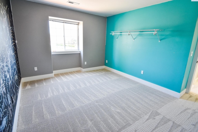 carpeted spare room with visible vents and baseboards