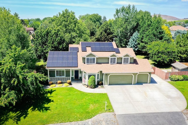 2780 Katie Rd, Kennewick, WA 99338 - traditional-style house featuring covered porch, solar panels, driveway, an attached garage, and roof with shingles
