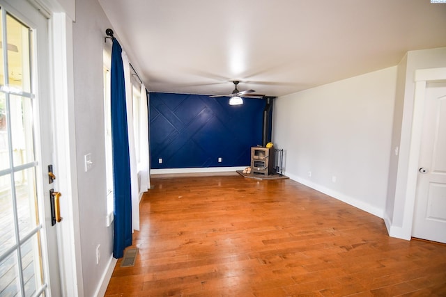 2780 Katie Rd, Kennewick, WA 99338 - spare room featuring a wood stove, a ceiling fan, baseboards, and light wood finished floors
