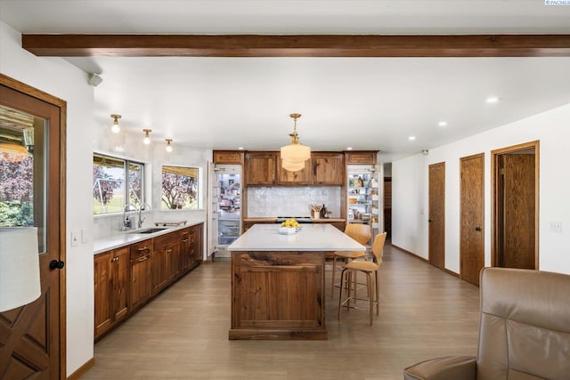 170732 Olsen Rd, Grandview, WA 98930 - kitchen featuring wood finished floors, beam ceiling, light countertops, decorative backsplash, and a center island