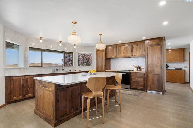170732 Olsen Rd, Grandview, WA 98930 - kitchen with range with electric stovetop, decorative backsplash, light wood-style floors, light countertops, and brown cabinetry