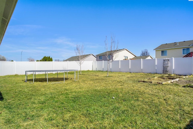 view of yard featuring a trampoline and a fenced backyard