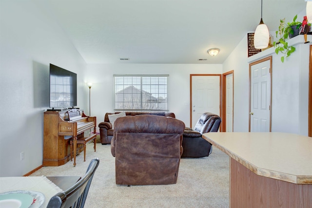 living area with visible vents, vaulted ceiling, and light colored carpet