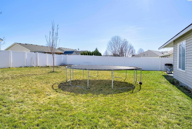 view of yard with a trampoline and a fenced backyard