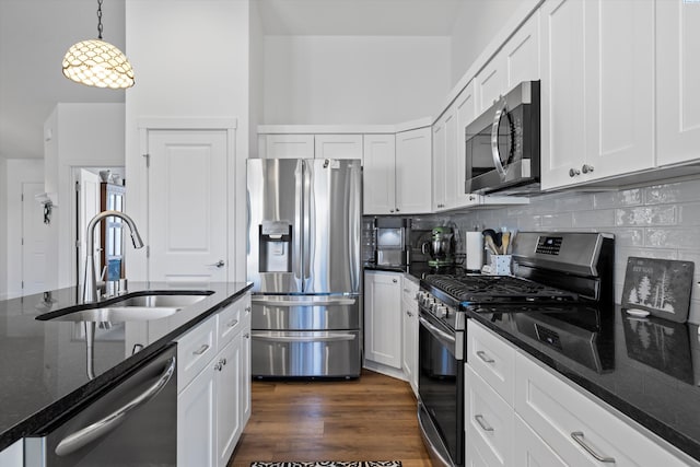 600 Lizzy Ln, Grandview, WA 98930 - kitchen featuring appliances with stainless steel finishes, dark wood-style floors, dark stone counters, decorative backsplash, and a sink