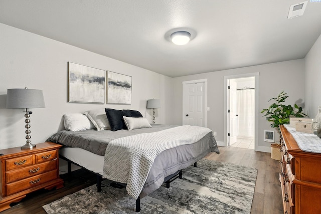 bedroom featuring dark wood-type flooring, baseboards, and ensuite bath