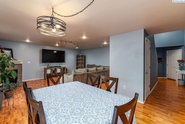 5309 Buchanan Ln, Pasco, WA 99301 - dining room with light wood-type flooring, baseboards, a textured ceiling, a fireplace, and recessed lighting