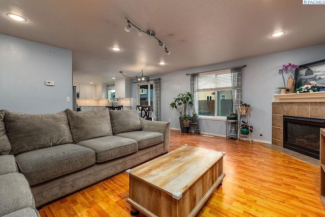 5309 Buchanan Ln, Pasco, WA 99301 - living area with recessed lighting, light wood-type flooring, a tiled fireplace, a textured ceiling, and baseboards