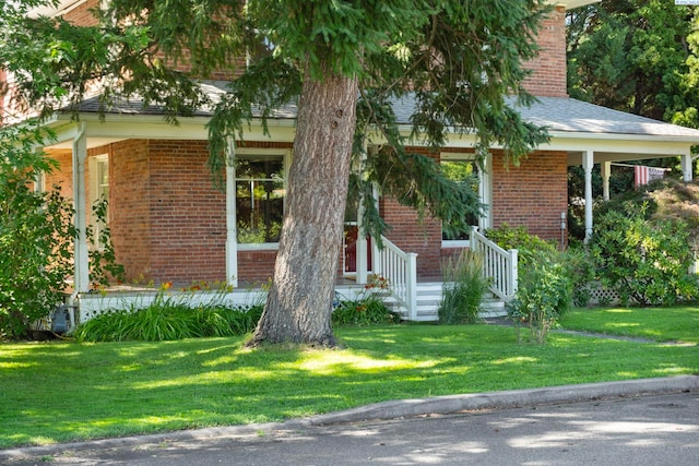 1002 Sherman Ave, Prosser, WA 99350 - obstructed view of property with brick siding, a front yard, covered porch, and a shingled roof