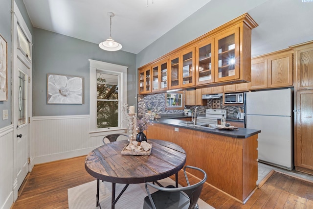 1002 Sherman Ave, Prosser, WA 99350 - kitchen featuring white appliances, a peninsula, hardwood / wood-style flooring, dark countertops, and a wainscoted wall
