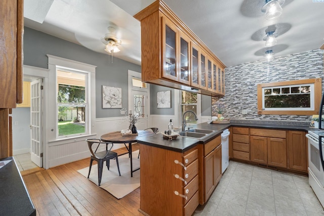 1002 Sherman Ave, Prosser, WA 99350 - kitchen featuring ceiling fan, white dishwasher, brown cabinetry, dark countertops, and wainscoting