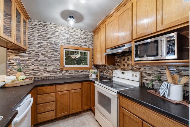 1002 Sherman Ave, Prosser, WA 99350 - kitchen with white appliances, under cabinet range hood, decorative backsplash, and dark countertops