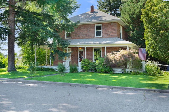 1002 Sherman Ave, Prosser, WA 99350 - view of front facade featuring a chimney, brick siding, a front yard, and covered porch