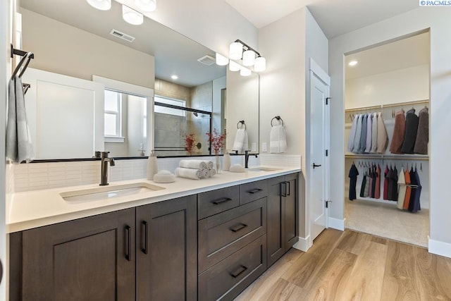 2864 Avrio Ave, Richland, WA 99354 - full bathroom with double vanity, a shower stall, decorative backsplash, a walk in closet, and wood finished floors